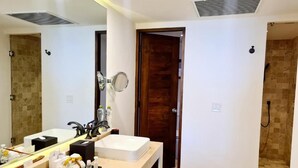 A modern bathroom with two sinks, a large mirror, and a shower area.
