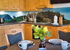 A kitchen with wooden cabinets, a dining table set with plates, cups, and a vase with flowers.