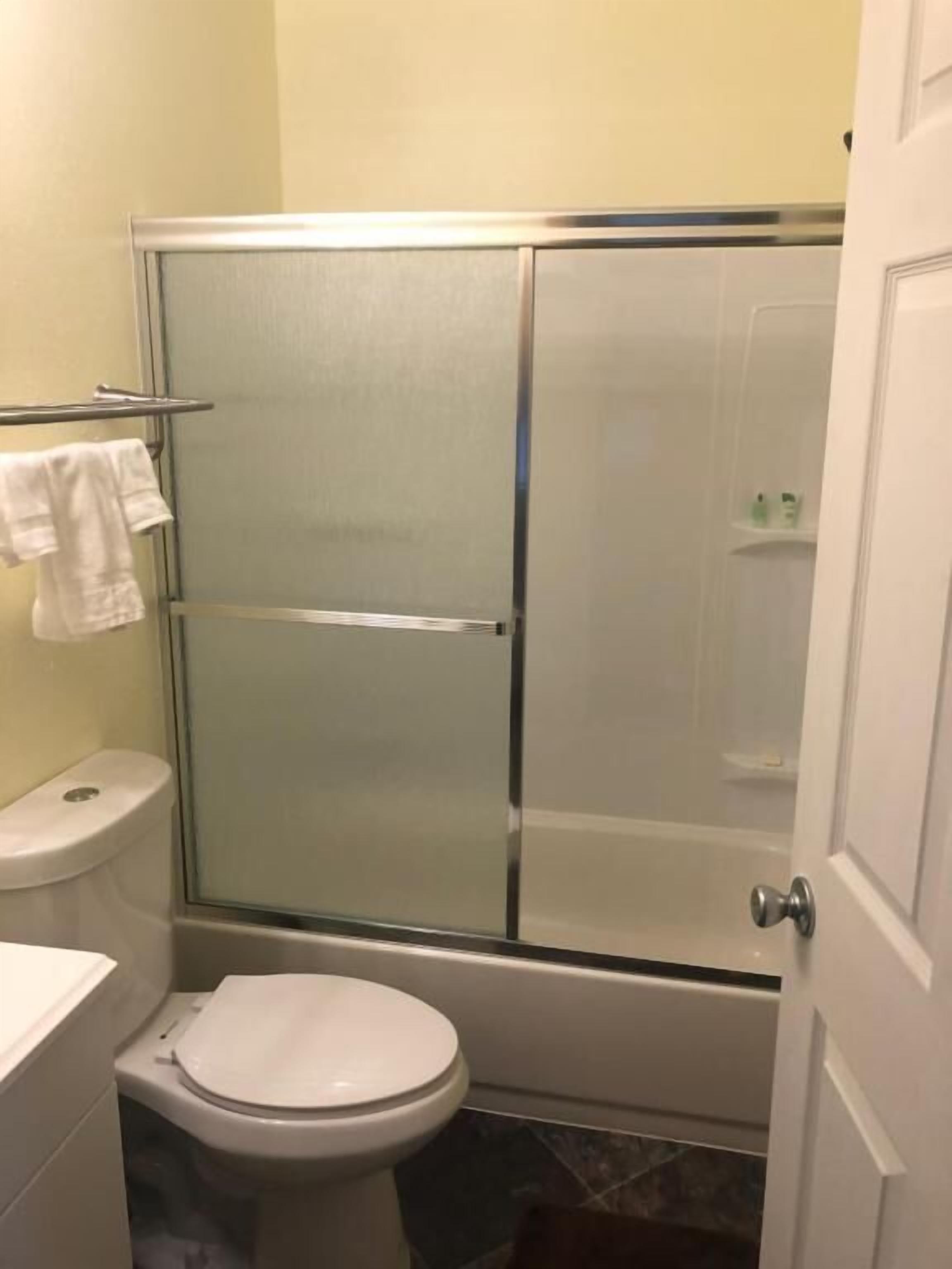 Un baño con ducha de vidrio, inodoro y perchero para toallas.