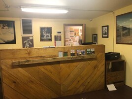 Un mostrador de recepción con detalles de madera, rodeado de cuadros enmarcados y carteles informativos.