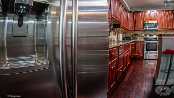Una cocina con electrodomésticos de acero inoxidable, armarios de madera y encimera de granito.