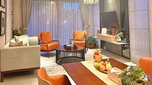 Una sala de estar moderna con comedor, que incluye una araña, sofás y una mesa de centro.