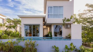 Una casa moderna de dos pisos con un balcón, ventanas grandes y una piscina pequeña.