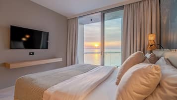 Una camera da letto con un letto, una televisione, vista sul tramonto e un'ampia finestra.