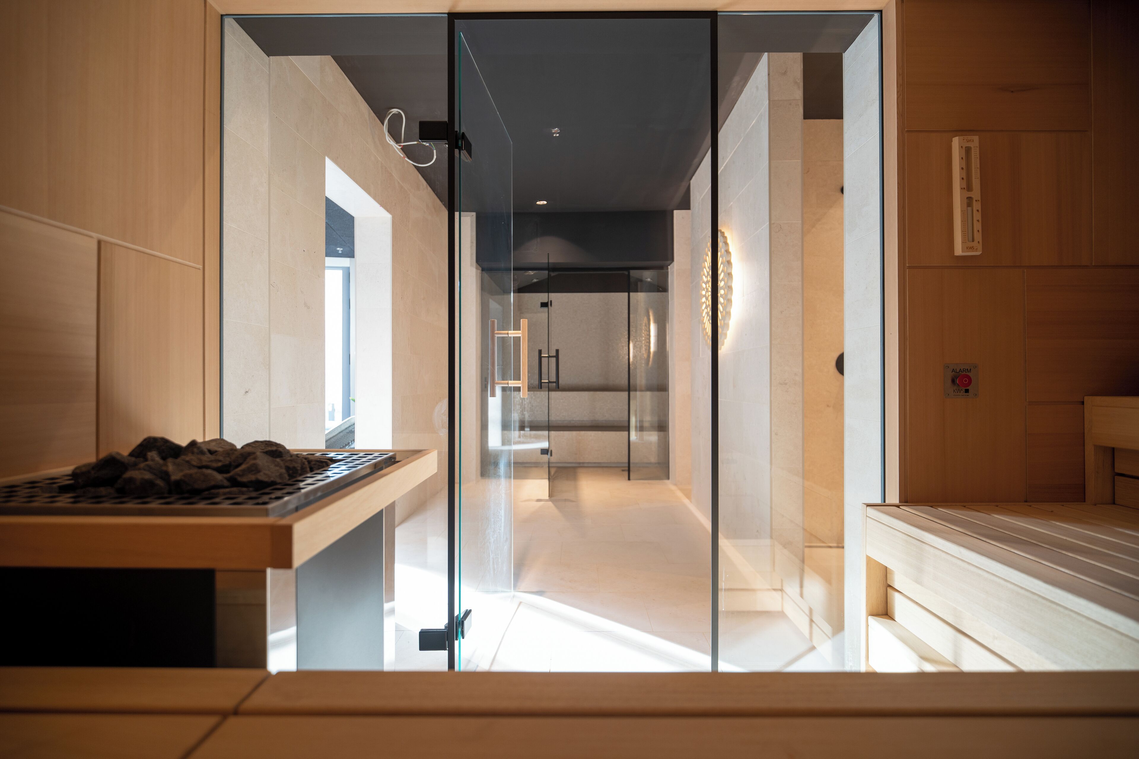 A modern interior with a wooden reception desk, a glass partition, and a sauna area.