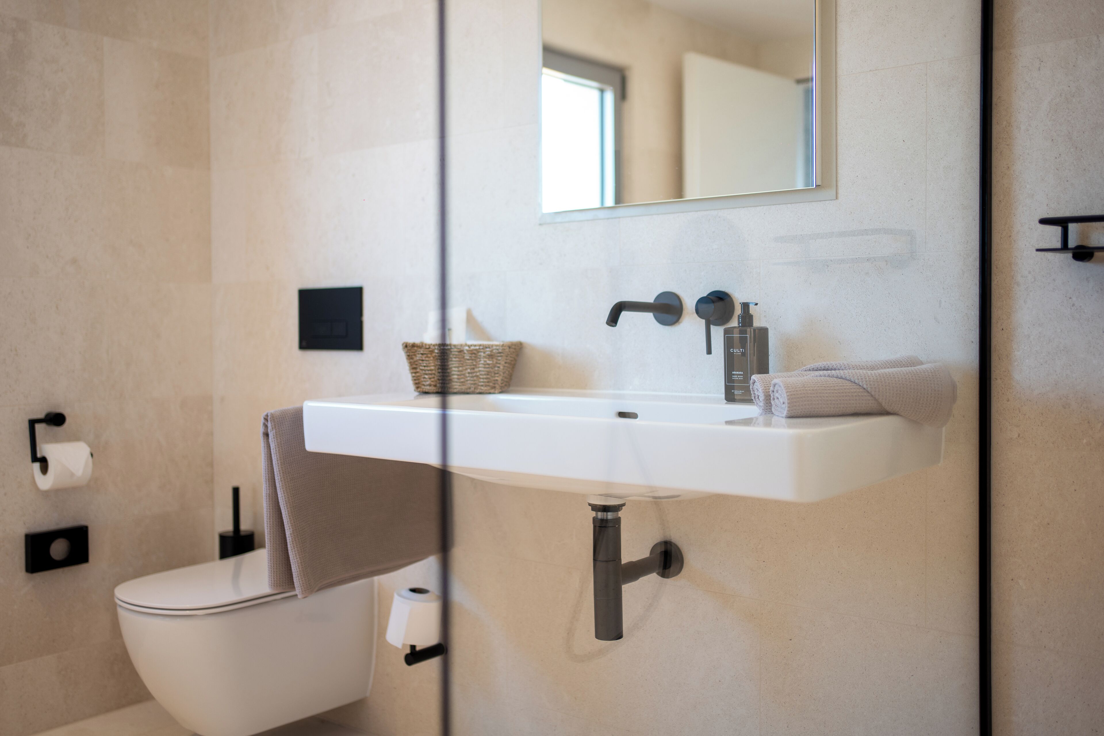 Een moderne badkamer met een wit wastafelmeubel, een spiegel, een handdoek en een toilet.