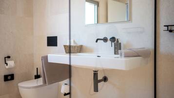 Een moderne badkamer met een wit wastafelmeubel, een spiegel, een handdoek en een toilet.
