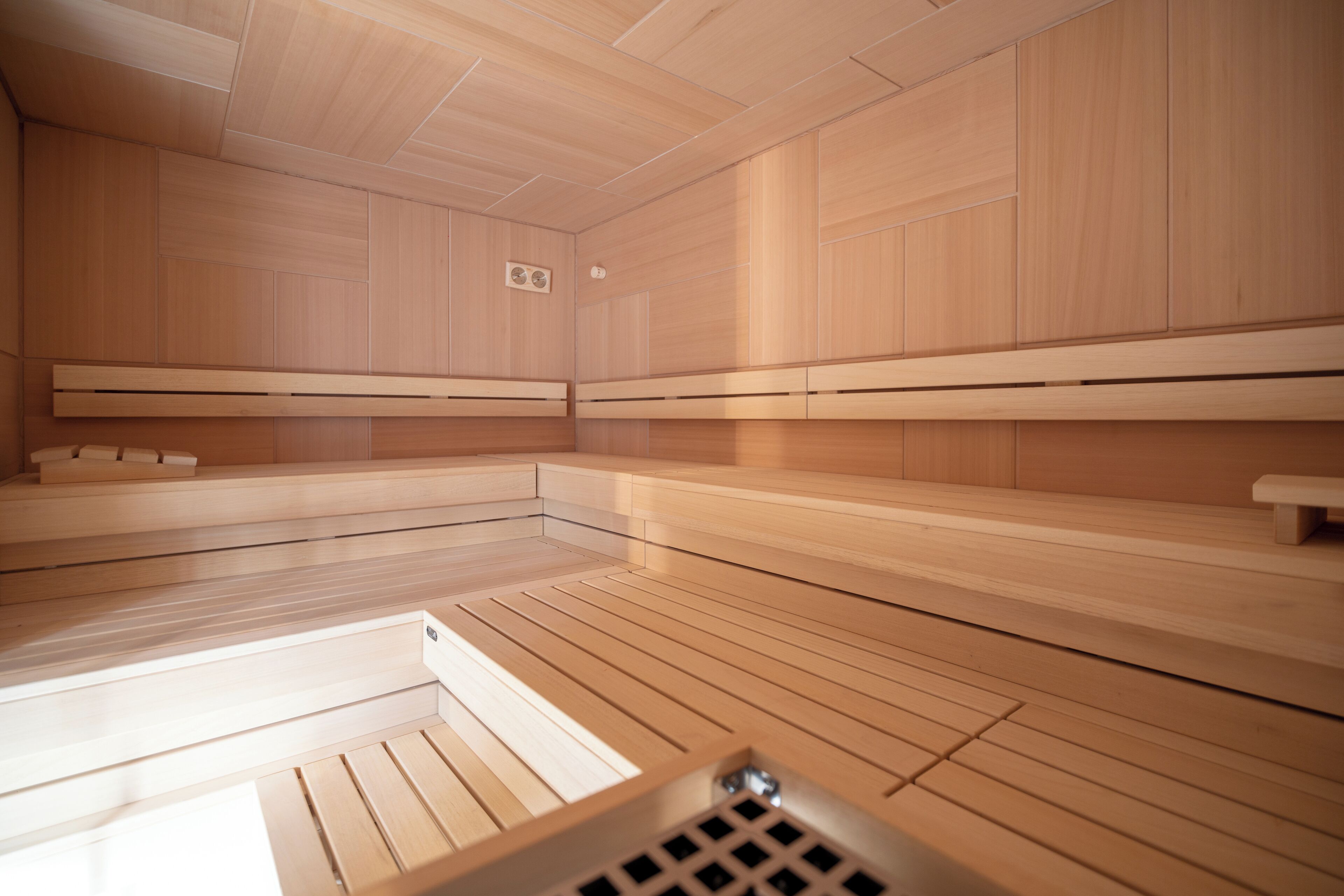 A sauna room with wooden benches and a sloped floor design.