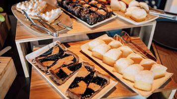 Un bufé con diversos postres, entre ellos pasteles, bollería y galletas.