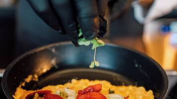 A person cooking in a pan with vegetables and eggs.