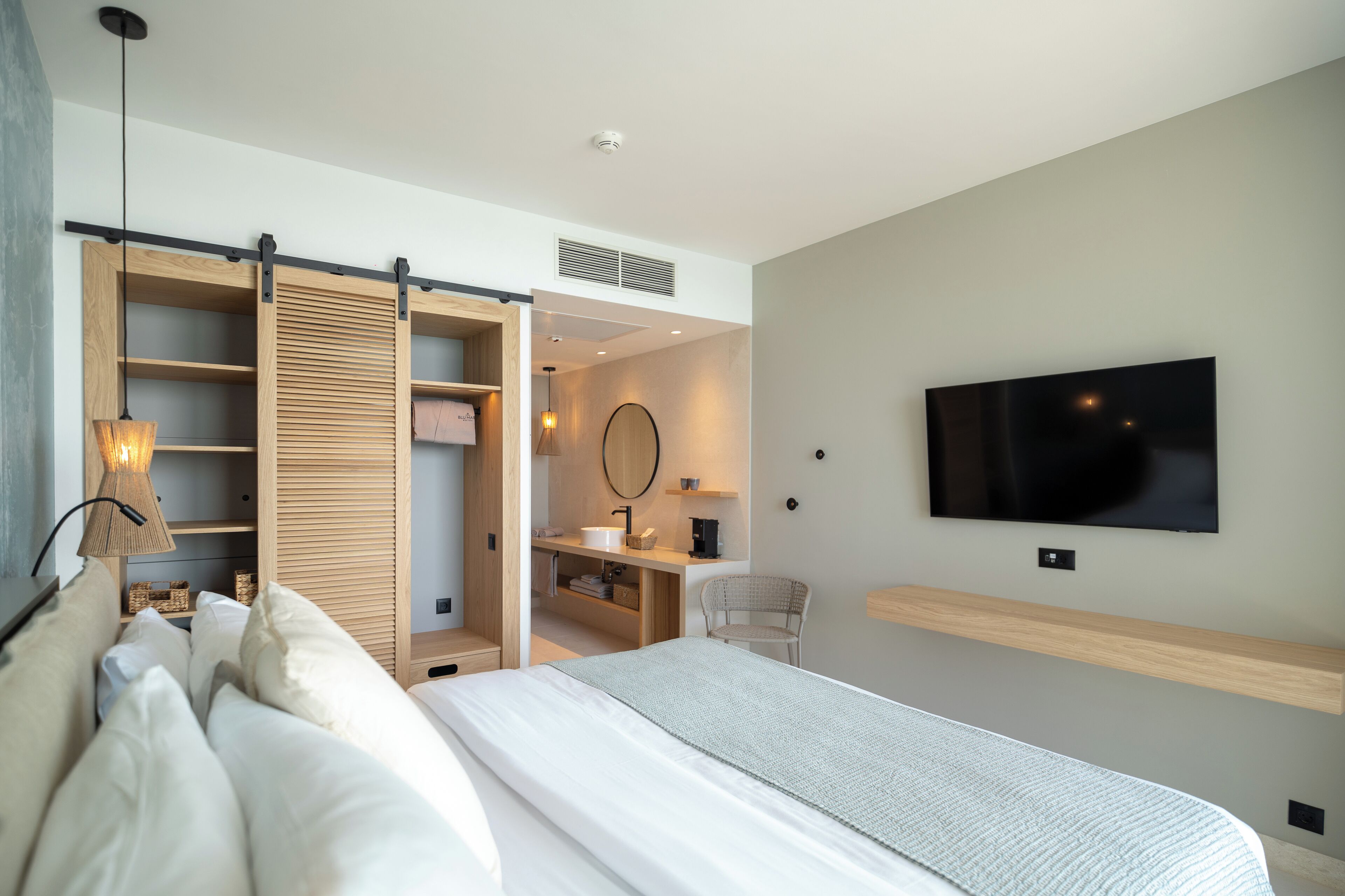 Un dormitorio moderno con una cama grande, un televisor instalado en la pared y un armario corredero.
