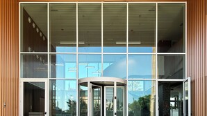 A modern building entrance with a revolving door and large glass windows. -  Valencia Tower (Burjasot)