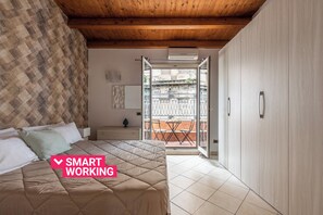 A bedroom with a bed, a nightstand, a dresser, and a balcony with a table and chairs. - San Domenico House by Wonderful Italy (Palermo)