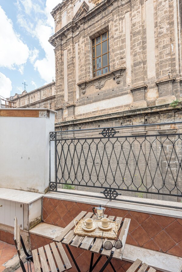 A terrace with a table set for two, a wrought iron gate, and a historic building in the background. - San Domenico House by Wonderful Italy (Palermo)