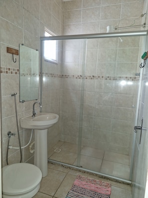 A bathroom with a glass-enclosed shower, a sink, and a toilet. - Pousada Encantus Penedo (Itatiaia)