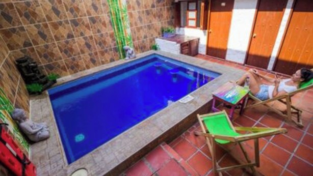 Ein kleiner Pool mit Fliesenverkleidung, ein Holzstuhl und ein Tisch.