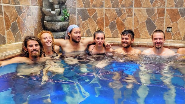A group of people in a hot tub with stone walls and a decorative fountain. - Fatima Hostel Santa Marta (Santa Marta)