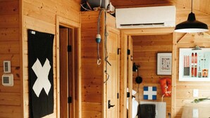 Puinen mökki, jonka sisustuksessa on musta sohva, valkoinen tyyny ja puinen katto.