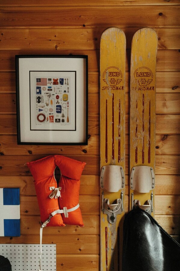 Un mur en bois orné de deux paires de skis, d’un tableau encadré et d’un coussin.