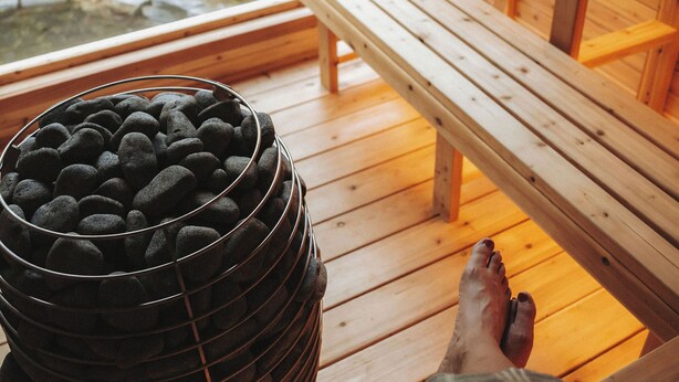 Una terraza de madera con un banco y una pila de piedras negras.