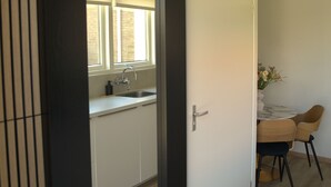 A modern kitchen with a window, a sink, and a dining area with chairs.