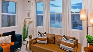 A living room with a blue sofa, a brown leather sofa, and a small table with a plant. - Luxe Lakefront Dream Villa: Heated Saltwater Pool (Indio)
