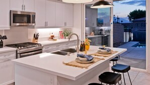 A modern kitchen with a large island, stainless steel appliances, and a view of the backyard. - Luxe Lakefront Dream Villa: Heated Saltwater Pool (Indio)