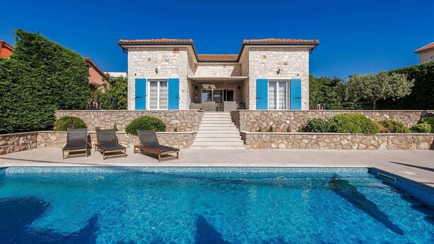 Ein zweistöckiges Steinhaus mit Swimmingpool, einer überdachten Terrasse und einer Treppe, die zum Eingang führt.