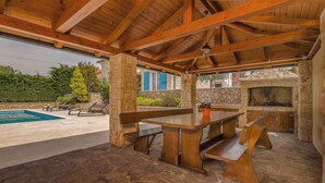 Eine Außenpatio mit Steinboden, Holzbanken und einem Pool.