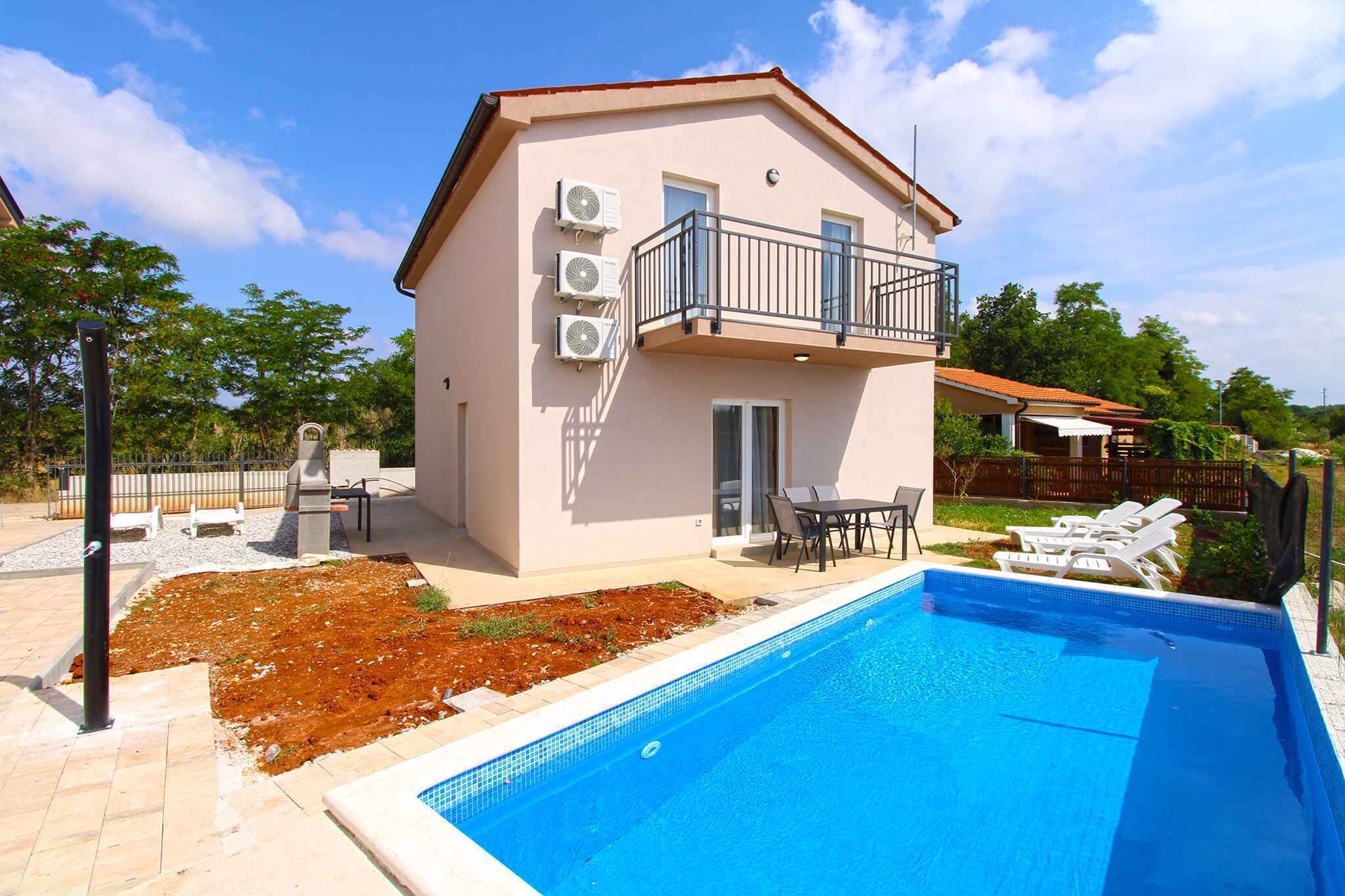 A two-story building with a balcony, a swimming pool, and outdoor seating.