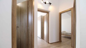 Un couloir avec des portes en bois et un lit visible au loin.