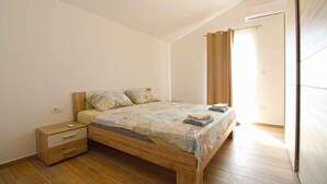 Une chambre à coucher avec un lit en bois, une table de chevet et une fenêtre avec des rideaux.
