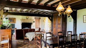 A traditional dining room with a wooden table and chairs, a fireplace, and exposed wooden beams on the ceiling. - 12 person property in Sologne (La Ferté-Imbault)