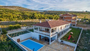 Une maison à deux étages avec une piscine, un espace extérieur aménagé pour se détendre et une aire de jeux pour enfants.