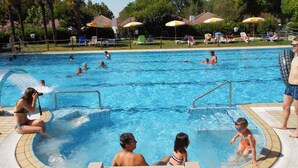 Una piscina con múltiples carriles, rodeada de sillas de descanso y sombrillas.