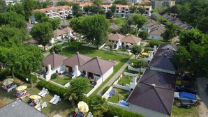 Una zona residencial con varias casas de dos pisos, algunas con techos planos y otras con techos inclinados. Hay varios árboles y algunos jardines pequeños.
