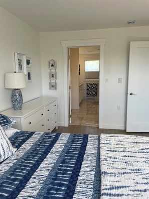 A bedroom with a bed, dresser, and a hallway leading to a bathroom. - Explore your own private beach and nature on 12 acres of ocean front property. (Lake Charlotte)