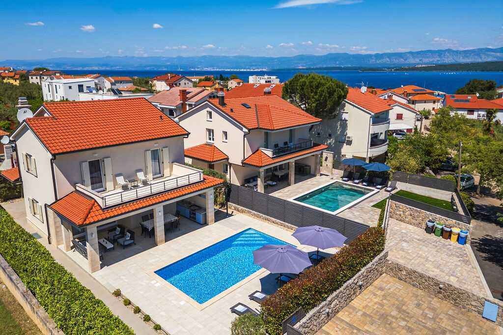 Una propiedad residencial con piscina, mobiliario de exterior y vistas al mar.