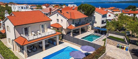 Ein Wohnhaus mit Schwimmbad, Sitzgelegenheiten im Freien und Blick aufs Meer.