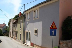Une rue résidentielle bordée de maisons, une voie étroite et un panneau de signalisation indiquant une voie de fusion.