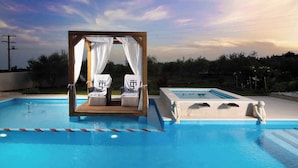 Un área de piscina con un toldo de madera y dos sillones de descanso, una piscina separada y una estatua.