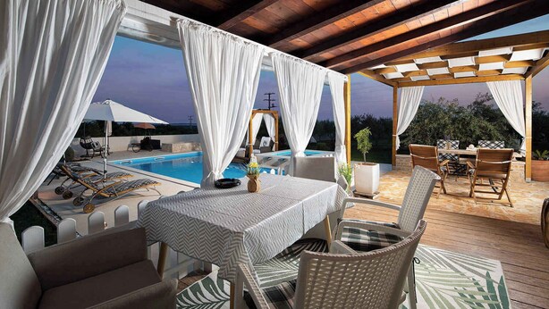Un patio al aire libre con piscina, zona de estar cubierta y una mesa con sillas.