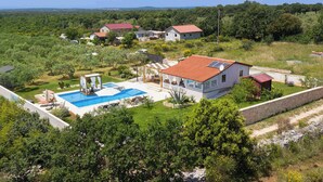 Propiedad residencial con piscina, varias casas y un paisaje verde exuberante.