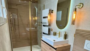 A modern bathroom with a glass shower enclosure, a wooden vanity with a white sink, and a large mirror with a gold frame. - Cocoon 5 minutes from town center and station (Amiens)