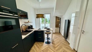 A modern kitchen with a herringbone wood floor, black cabinets, and a central island with stools. - Cocoon 5 minutes from town center and station (Amiens)