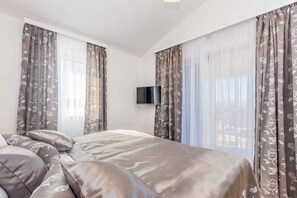 Een slaapkamer met een bed, gordijnen en een televisie.