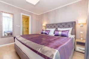 Une chambre à coucher avec un grand lit, un miroir, une table de chevet et une lampe fixée au mur.