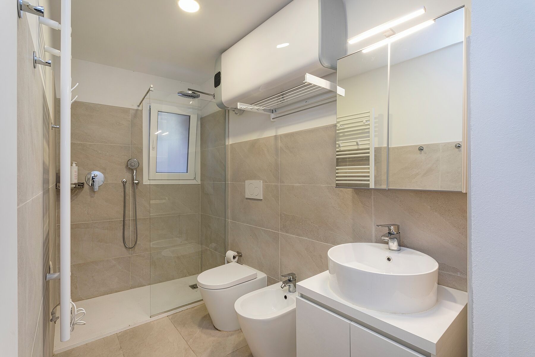 A modern bathroom with a glass-enclosed shower, a toilet, and a double sink vanity.
