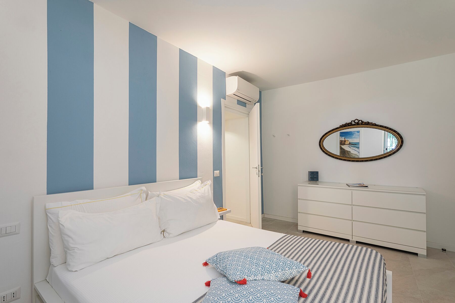 A bedroom with a bed, a dresser, a mirror, and a door.