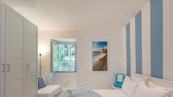 Ein Schlafzimmer mit Bett, Schreibtisch und einem Fenster mit Meerblick.